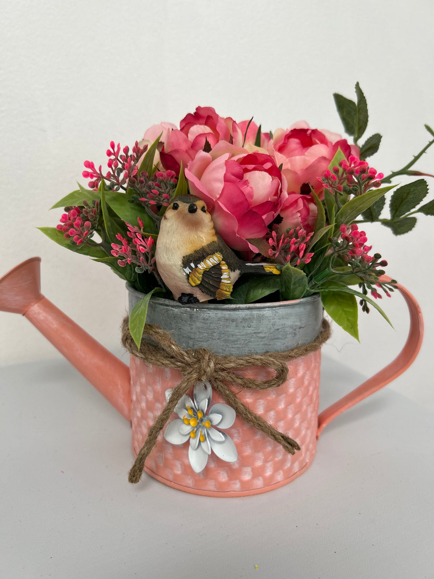 Coral Watering Can filled with artificial flowers and bird figure